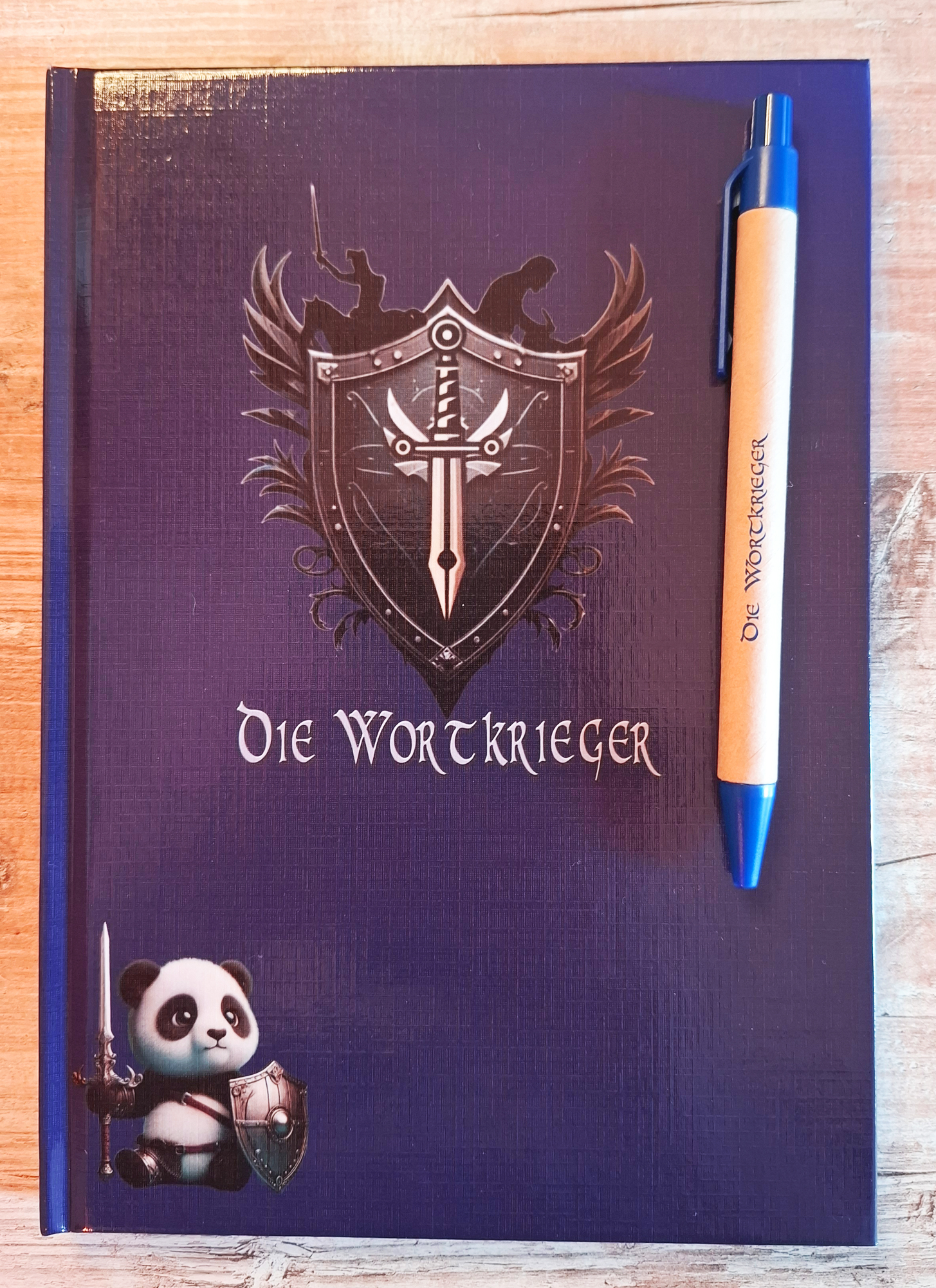Notizbuch mit Stift mit dem Logo der Wortkrieger, sowie dem Maskottchen, dem Pandabären